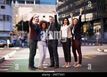 Das beste Team der Stadt. Ein motiviertes Business-Team, das seine Hände für den Erfolg hochlegt, während es mitten auf einer Straße steht. Stockfoto