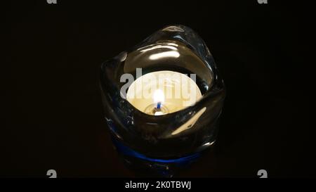 Kerzenlicht in Glas kleinen Glas. Dunkle Nacht Hintergrund Stockfoto