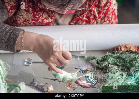 Fabrikarbeiterin stickt Seide. Foto: Bo Arrhed Stockfoto