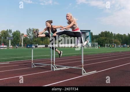 Zwei Laufsportlerinnen laufen im Stadion im Freien Hürden Stockfoto