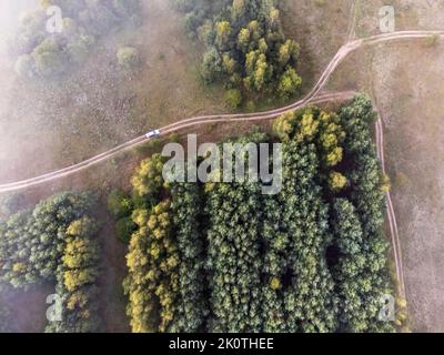 Bilder vom Drohnenflug über den Nebel. Fluss, Wald, Felder und Wiesen in nebliger Sommerdämmerung. Stockfoto