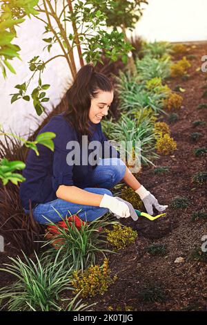 Einen Garten zu Pflanzen heißt an morgen zu glauben. Eine junge Frau, die in ihrem Garten arbeitet. Stockfoto