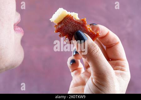 Nahaufnahme der Hand einer Frau, die ihr Guava-Süße und Käse in den Mund nimmt. Stockfoto