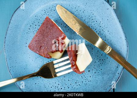 Nahaufnahme einer goldenen Gabel mit Stücken von Guava-Süße und Käse auf einem Teller. Stockfoto