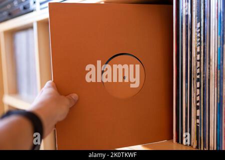 Nahaufnahme der Hand einer Person, die eine Schallplatte aus seiner Plattenbibliothek hält. Musikhören Konzept. Stockfoto