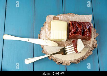 Goldene Gabel mit Guava-Süße und Käse auf einem Holzteller, neben einer Messeransicht. Stockfoto