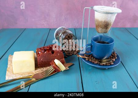 Goldene Gabel mit Stücken Guava süß mit Käse neben Messer, Bohnen und Tasse Kaffee. Stockfoto