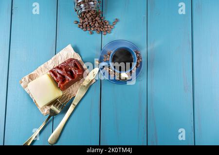 Guava süß mit Käse auf braunem Papier, umgeben von Besteck, Bohnen und einer Tasse Kaffee top-Ansicht. Stockfoto