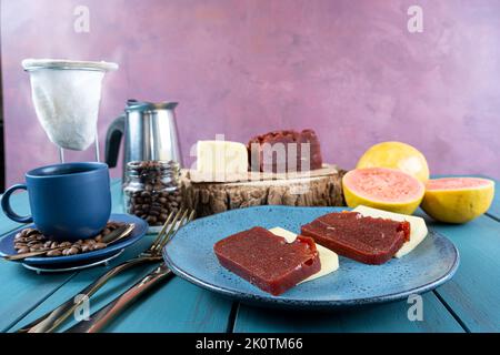 Guava süß mit Käse, umgeben von einer Tasse und Kaffeebohnen auf einer blauen Tischseite. Stockfoto