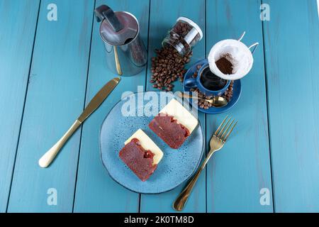 Guava süß mit Käse, umgeben von Besteck, Tasse und Kaffeebohnen auf einem blauen Table Top-Blick. Stockfoto