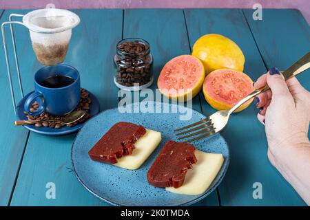 Frau bereit, Guava süß mit Käse zu pflücken, umgeben von Bohnen und einer Tasse Kaffee. Stockfoto