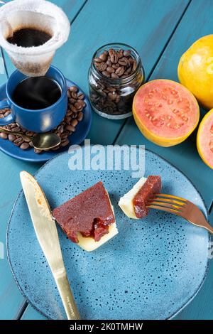 Gabel mit Stücken von Guava süß mit Käse neben Messer, Bohnen und Kaffeetasse. Stockfoto