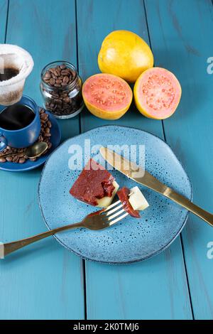 Gabel mit Stücken von Guava süß mit Käse auf dem Teller ruhen, neben Bohnen und Tasse Kaffee. Stockfoto