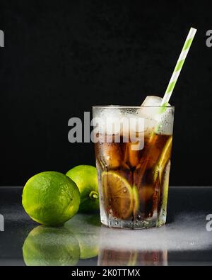 Cuba Libre Cocktail mit Limette auf schwarzem Hintergrund. Stockfoto