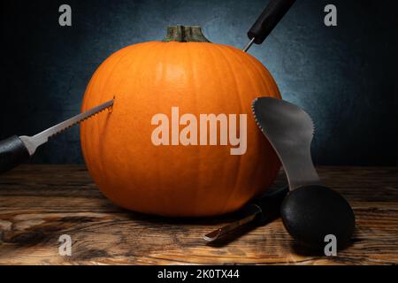 Halloween Kürbisschnitzwerkzeuge für Jack-o'-Lantern-Gesichtsausschnitt. Löffelrinne und Sägeblätter, mit orangefarbenem HerbstKürbis. Stockfoto