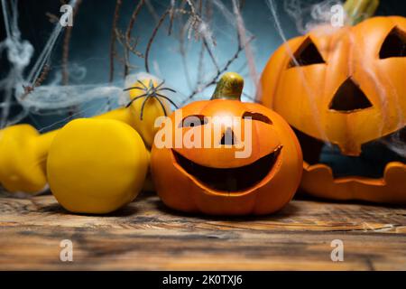 Kurzhanteln und gruselige Halloween-Figuren aus Keramik, Kürbisse mit Spinnennetz bedeckt. Fitness Herbst oder Herbst Komposition, Gym Workout, Trainingskonzept. Stockfoto