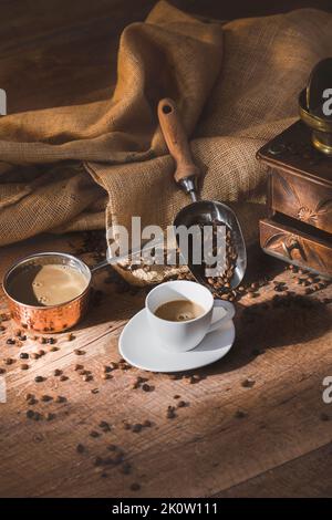 Tasse Latte-Kaffee mit Kanne und Kaffeebohnen Stockfoto