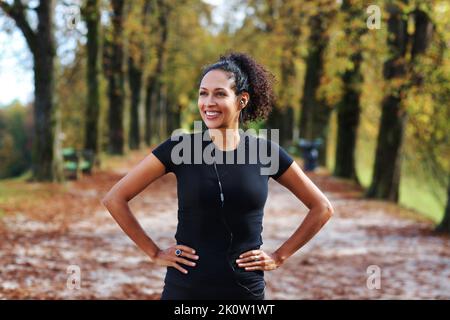 Positive Frau, die sich im Freien dehnt, bereitet sich auf Sport in Sportbekleidung vor Stockfoto