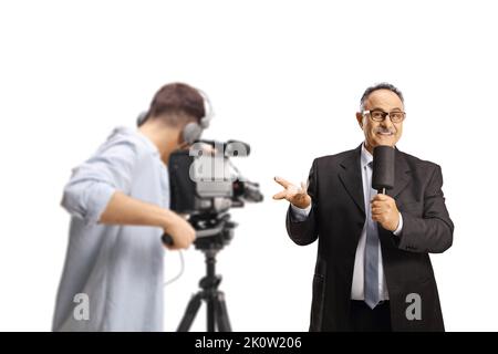 Kameramann, der einen männlichen fernsehmoderator mit einem Mikrofon aufzeichnet, das mit isolierter Hand auf weißem Hintergrund gestikelt wird Stockfoto