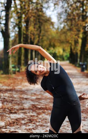 Positive Frau mittleren Alters Stretching im Freien Vorbereitung auf die Ausübung in Sportbekleidung Stockfoto