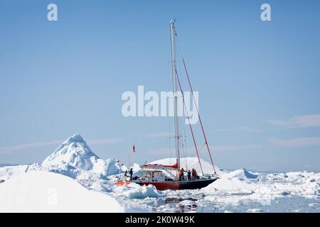 Yacht navigiert am 17. Juli 2022 durch dicht gepackte Eisberge im Ilullisat-eisfjord, Grönland Stockfoto