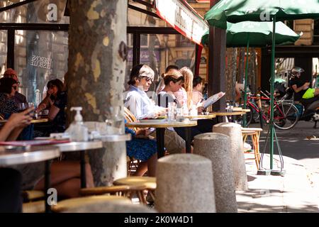 Paris, Frankreich - Juli 15: Am 15. Juli 2022 sitzt ein Mann in einem Café, während andere Leute die Zeitung lesen Stockfoto