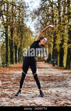 Positive Frau mittleren Alters Stretching im Freien Vorbereitung auf die Ausübung in Sportbekleidung Stockfoto