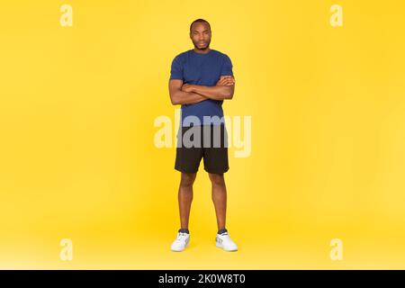 Serious Black Sportsman Standing Crossing Hands Posiert Auf Gelbem Hintergrund Stockfoto