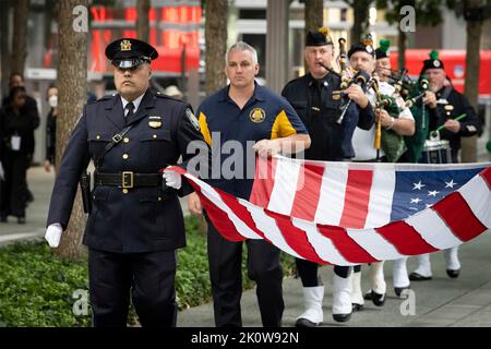 New York, Vereinigte Staaten von Amerika. 11. September 2022. Ein Polizeibeamter der New Yorker Polizei trägt eine amerikanische Flagge während der Zeremonie zur Erinnerung an die Opfer der Anschläge von 9/11 im National September 11 Memorial Museum am 11. September 2022 in New York City. Die Nation feierte den 21.. Jahrestag der Angriffe von al-Qaida-Terroristen, bei denen fast 3.000 Menschen getötet wurden. Kredit: Sydney Phoenix/DHS Foto/Alamy Live Nachrichten Stockfoto