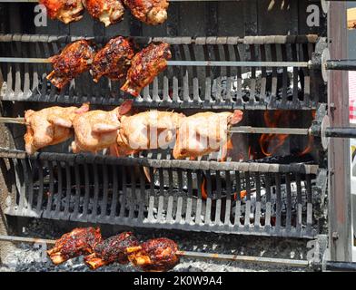 Hühner und Schweineknöchel am Spieß im großen Restaurant während des Dorffestes Stockfoto