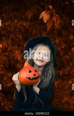 Halloween. Das Mädchen lacht und hält einen Kürbis in den Händen. Stockfoto