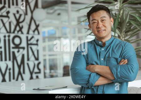 Porträt eines lächelnden asiatischen Geschäftsmannes, der im Büro steht Stockfoto