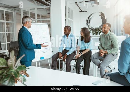 Ein männlicher Business-Coach oder Sprecher präsentiert bei Meetings den verschiedensten Geschäftsleuten Flipchart-Präsentationen Stockfoto