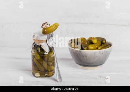 Eingelegte Gurken, Gewürze und Knoblauch auf weißem Holztisch konservieren Stockfoto