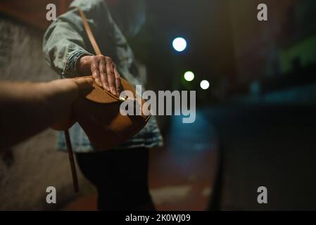 Dieb schnappt der Frau auf der Nachtstraße einen Beutel. Stockfoto