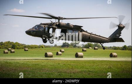 Ein Feld von Heuballen umrahmt einen Iowa Army National Guard UH-60 Black Hawk, der sich auf die Schlinge eines Anhängers während eines U.S. Pathfinder Course am 8. September 2022 in Camp Dodge in Johnston, Iowa, vorbereitet. Fast 30 Soldaten absolvierten den Kurs, der von einem mobilen Trainingsteam im Warrior Training Center der Army National Guard in Fort Benning, Georgia, unterrichtet wurde. Army Pathfinders werden geschult, um Navigationshilfe und Beratungsdienste für Militärflugzeuge in Gebieten zu leisten, die von unterstützten Einheiten-Kommandeuren bestimmt werden. Während des Pathfinder-Kurses werden die Studenten in der Flugzeugorientierung, Aero-Medical ev, unterwiesen Stockfoto