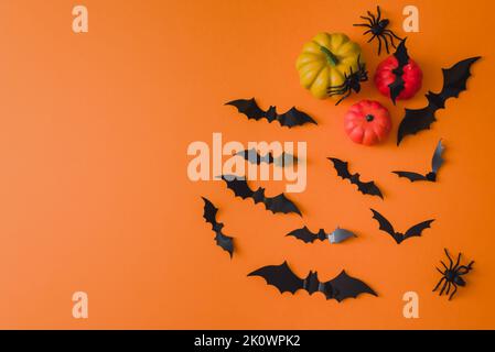 Frohe halloween-Feiertage. Halloween-Dekorationen, Fledermäuse, Spinnen, Kürbisse auf orangefarbenem Hintergrund. Flach liegend, Draufsicht. Stockfoto
