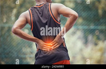 Athletischer, fulger Mann mit Schmerzen im unteren Rücken, Halt im Freien und Massagen müde und strapazieren Muskeln oder Rückenmarksverletzungen. Muskulöser schwarzer Mann mit Krämpfen Stockfoto