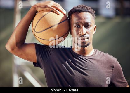 Porträt afroamerikaner, der mit einem Basketball auf dem Platz steht. Fitness-Athlet oder -Spieler, der nach dem Spielen oder Training einen Sportball hält Stockfoto