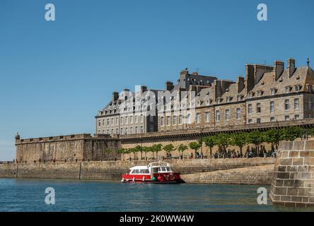 St. Malo, Bretagne, Frankreich - 8. Juli 2022: Kleine rote Fähre legt am Quai de Dinan mit Bastion Saint Philippe an der vorderen Ecke unter blauem Himmel an. Sockel Stockfoto