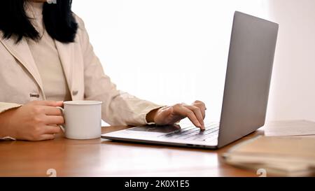 Abgeschnitten und Nahaufnahme Bild, Eine erfolgreiche asiatische Geschäftsfrau arbeitet an ihren geschäftlichen Aufgaben auf Notebook-Laptop-Computer. Stockfoto