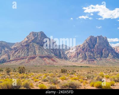 Nevada Wüstenlandschaft mit Felsauftrieb, die Eisenoxid-rote Streifen unter blauem Himmel zeigt Red Rock Canyon in der Mojave Wüste. Stockfoto