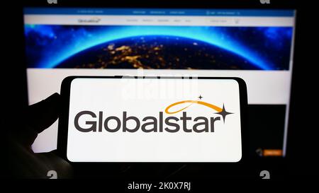 Person, die das Smartphone mit dem Logo des Satellitenkommunikationsunternehmens Globalstar Inc. Auf dem Bildschirm vor der Website hält. Konzentrieren Sie sich auf die Telefonanzeige. Stockfoto