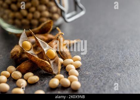 Sojabohnen. Getrocknete Sojabohnenschote auf dem schwarzen Tisch. Stockfoto