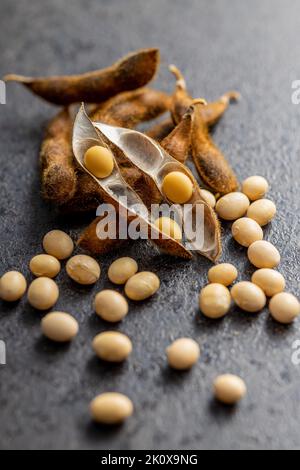 Sojabohnen. Getrocknete Sojabohnenschote auf dem schwarzen Tisch. Stockfoto