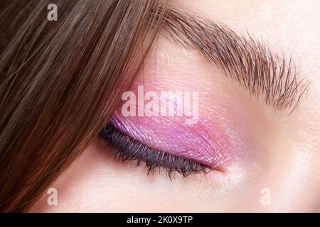 Nahaufnahme eines geschlossenen menschlichen weiblichen Auges. Frau mit natürlichen Abend vogue Gesicht Schönheit Make-up. Mädchen mit perfekter Haut und rosa Augen Schatten. Stockfoto