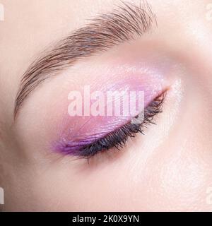 Nahaufnahme eines geschlossenen menschlichen weiblichen Auges. Frau mit natürlichen Abend vogue Gesicht Schönheit Make-up. Mädchen mit perfekter Haut und rosa Augen Schatten. Stockfoto