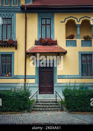 Bunte Hausfassade, Vintage-Stil mit Retro-Veranda und Markise. Traditionelles europäisches Gebäude von außen, Vorderansicht an der Eingangstür Stockfoto