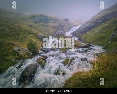 Schneller Bach, der durch ein felsiges Tal in den Fagaras Mountains fließt. Fluss mit Wasserfällen und dichter Nebellandschaft Stockfoto