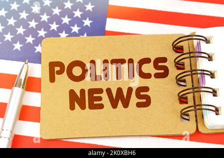 Politik und Menschen Konzept. Auf der US-Flagge liegt ein Notizbuch mit der Aufschrift - Politics News Stockfoto